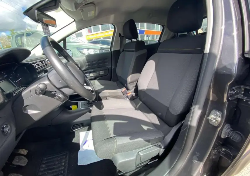 Vue intérieure côté conducteur de la Citroën C3 gris platinium, montrant les sièges avant et le volant.