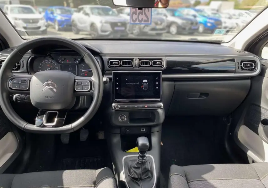 Vue intérieure avant du poste de conduite de la Citroën C3 2021, tableau de bord noir avec écran tactile central et volant multifonction.