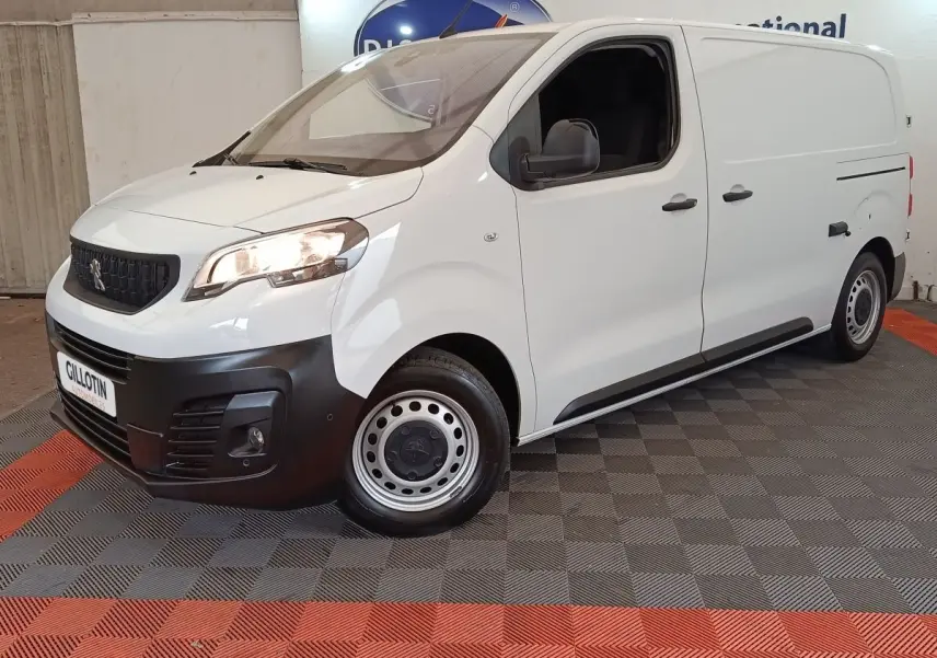 Vue 3/4 avant droit d’un Peugeot Expert Fourgon blanc avec pare-chocs noir et jantes acier, stationné en intérieur.
