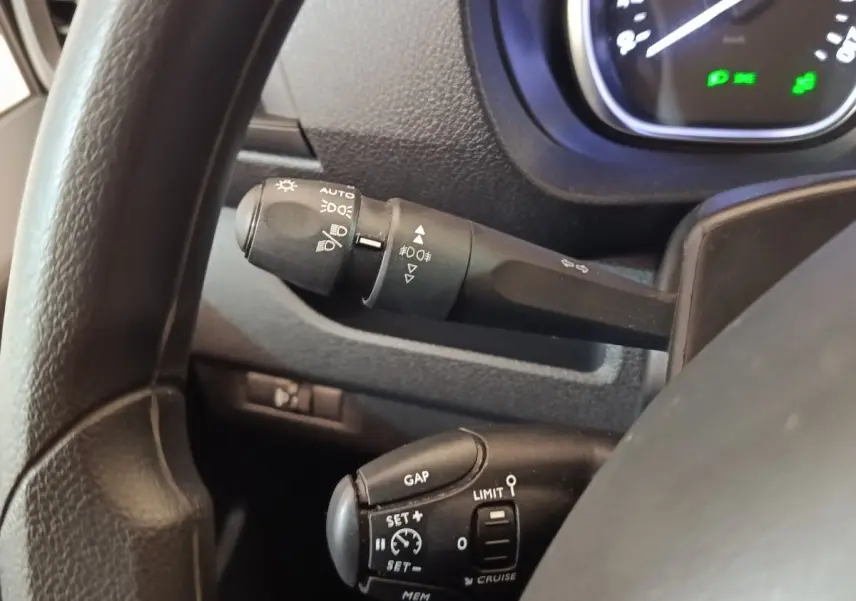Gros plan sur le volant noir du Peugeot Expert Fourgon, montrant les commandes de régulateur et des phares.