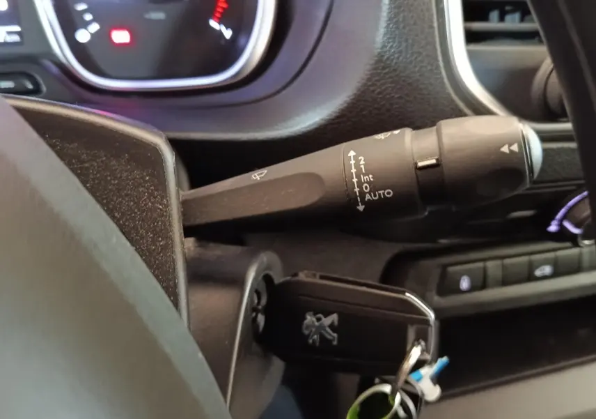 Gros plan sur la clé insérée et le commodo d’essuie-glace côté gauche du tableau de bord du Peugeot Expert Fourgon blanc.