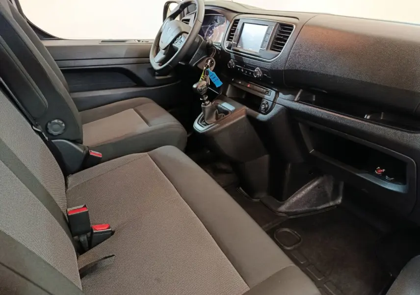 Vue intérieure côté conducteur du Peugeot Expert Fourgon blanc 2023, montrant le tableau de bord et les sièges avant gris.