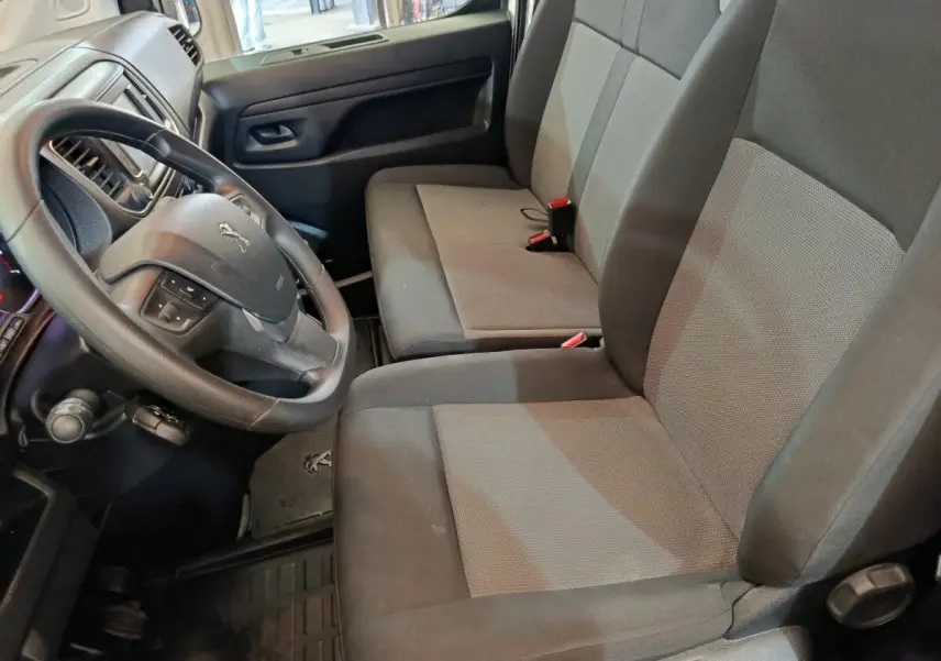 Vue intérieure côté conducteur du Peugeot Expert Fourgon 2023, sièges tissu gris et volant multifonctions noir.