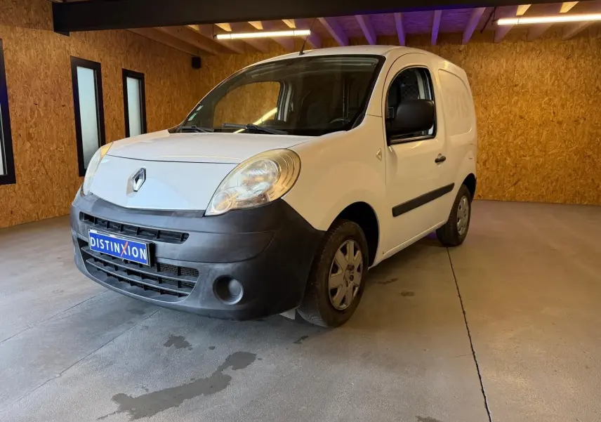 Renault Kangoo blanc 2011 en 3/4 avant droit, avec pare-chocs noir mat et plaque Distinxion visible.