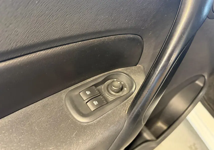 Gros plan sur la commande des vitres électriques côté conducteur du Renault Kangoo blanc de 2011, intérieur noir.
