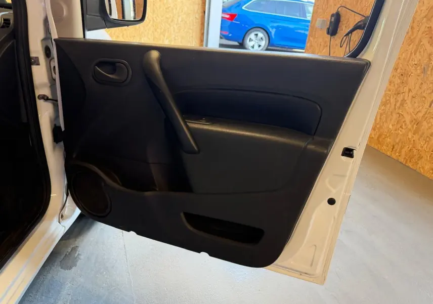 Vue intérieure de la porte avant gauche blanche d’un Renault Kangoo 1.5 DCI 85 Compact avec panneau noir et haut-parleur intégré.