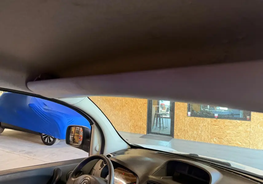 Vue intérieure du Renault Kangoo blanc 2011, montrant le tableau de bord et le volant côté gauche avec intérieur noir.