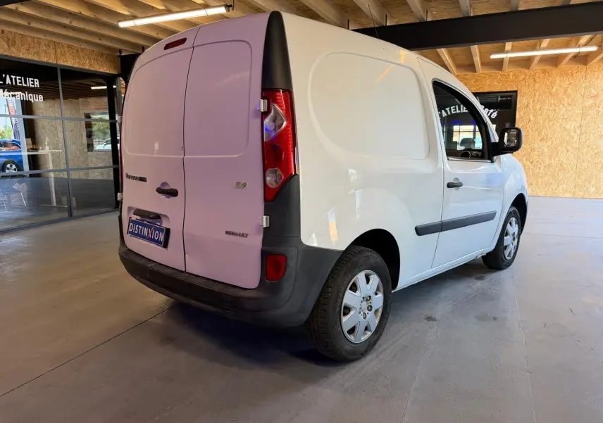 Renault Kangoo blanc vue 3/4 arrière droit dans un garage avec portes arrière fermées et pare-chocs noirs.