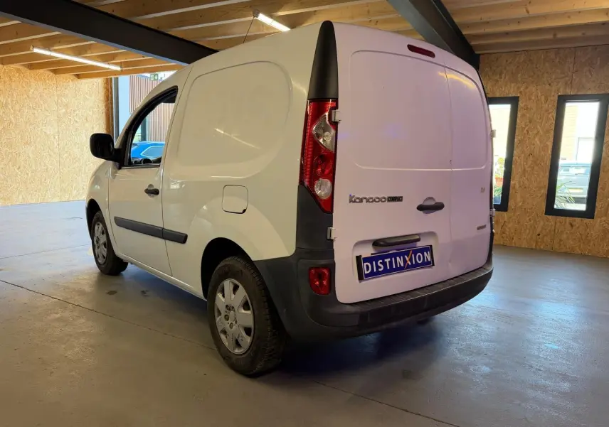 Vue 3/4 arrière droite d'un Renault Kangoo blanc 2011 version Compact, utilitaire avec portes arrière pleines en intérieur d'entrepôt.