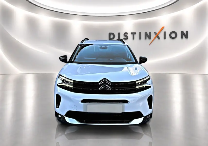Vue frontale d'un Citroën C5 Aircross blanc 2025 avec calandre noire et barres de toit visibles en studio lumineux.