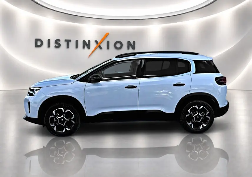 Profil droit du Citroën C5 Aircross blanc avec jantes noires et toit noir dans un showroom lumineux.