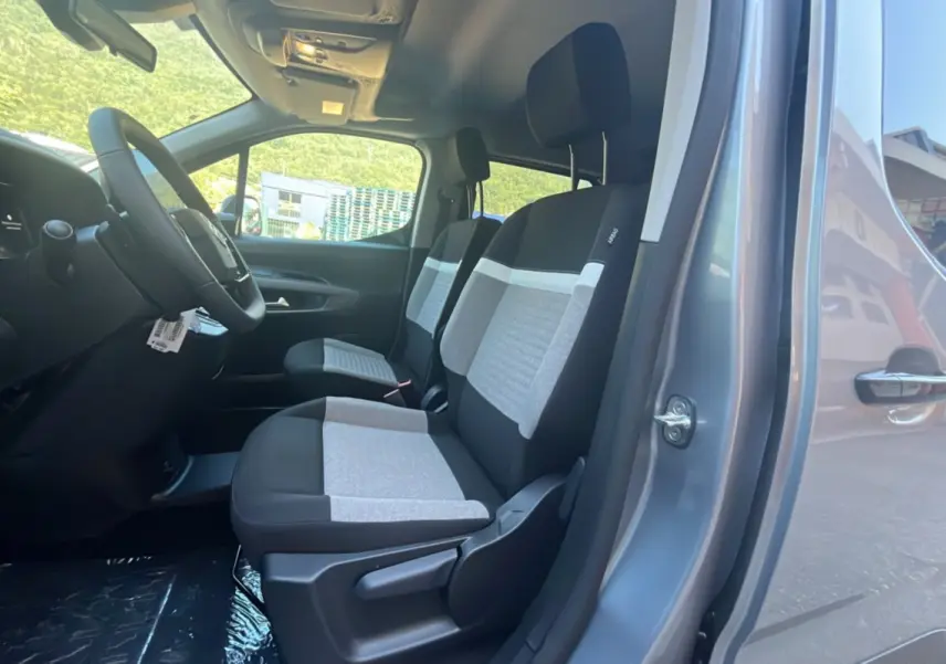 Vue intérieure côté gauche du Citroën Berlingo gris Artense 2026, montrant les sièges avant bi-ton tissu gris et noir.