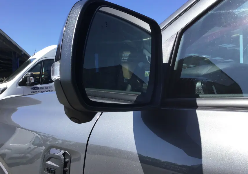 Rétroviseur côté gauche du Ford Ranger Double Cabine gris carbone, avec reflet de l'habitacle et caméra intégrée.