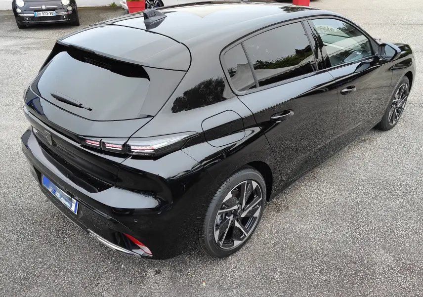 Vue 3/4 arrière droite de la Peugeot 308 PureTech 130 Allure Pack noire avec jantes bi-ton et feux LED distinctifs.