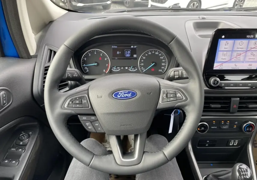 Vue intérieure centrée sur le volant Ford d'un EcoSport bleu Island, avec tableau de bord et écran tactile visibles.