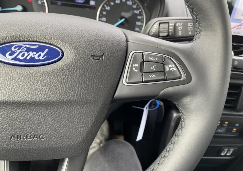 Gros plan sur le volant noir du Ford EcoSport 2022 avec commandes audio intégrées et logo Ford bleu au centre.