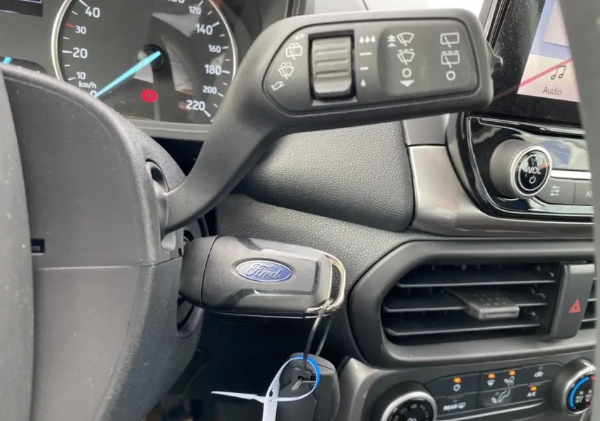Vue rapprochée de l’intérieur du Ford EcoSport 2022, clé dans le contact et commandes de climatisation visibles.