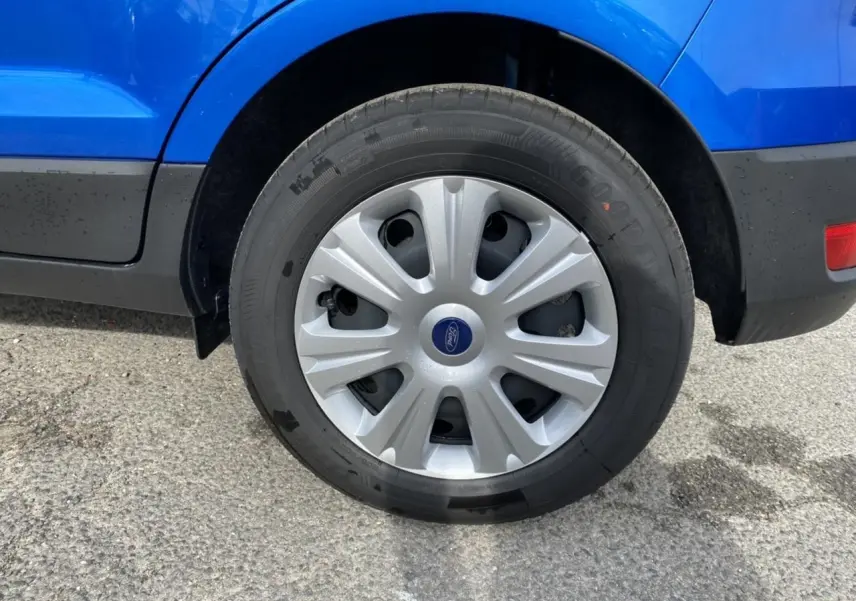 Gros plan sur la roue arrière droite d’un Ford EcoSport bleu Island avec enjoliveur argenté et logo Ford central.