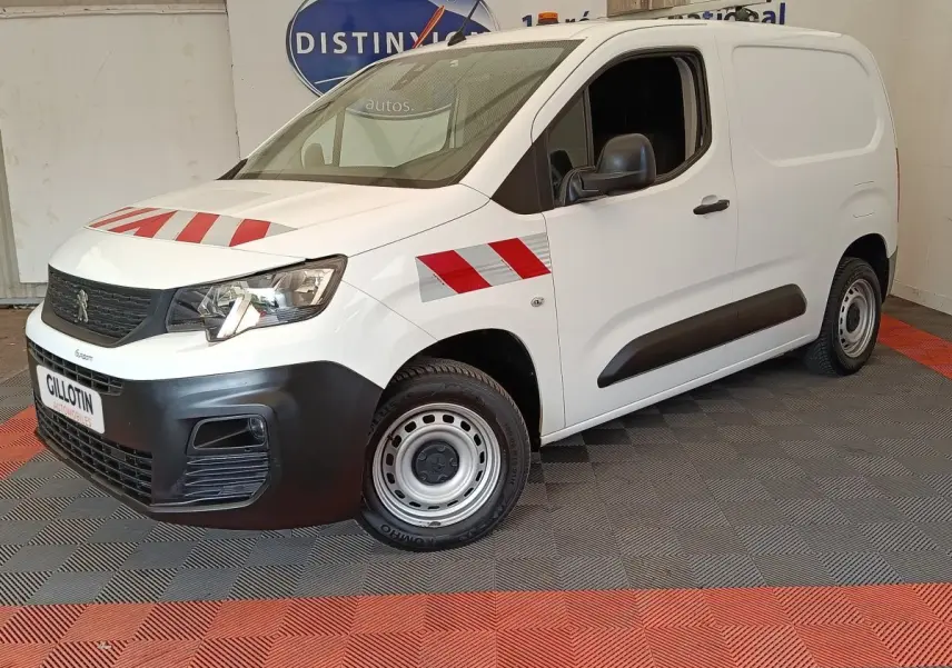Vue 3/4 avant droit d’un Peugeot Partner blanc avec bandes rouges réfléchissantes sur capot et aile avant.