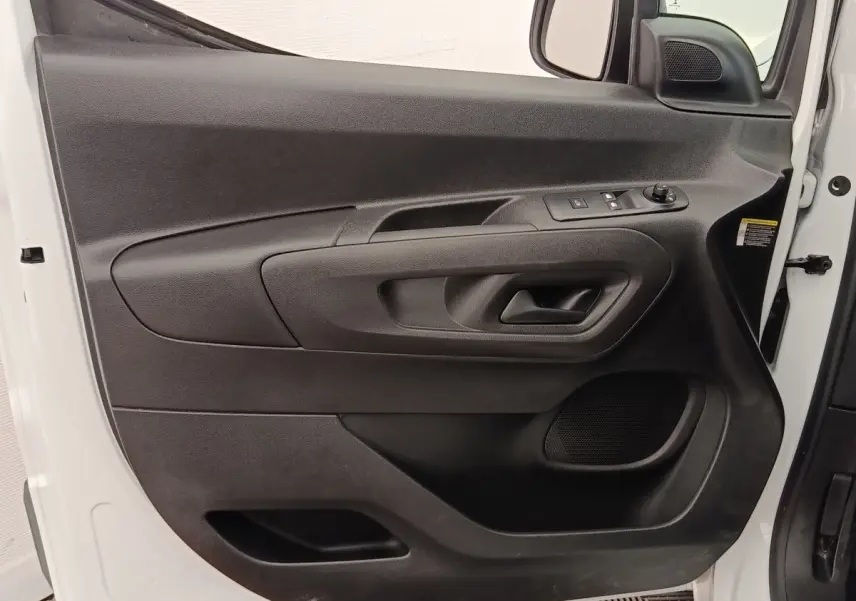 Vue rapprochée de la porte avant gauche noire du Peugeot Partner blanc, avec commandes de vitres et haut-parleur intégré.