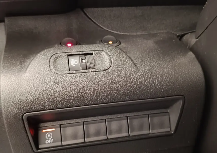 Gros plan sur le tableau de bord noir du Peugeot Partner 2022, montrant les commandes de réglage des phares et désactivation du start-stop.