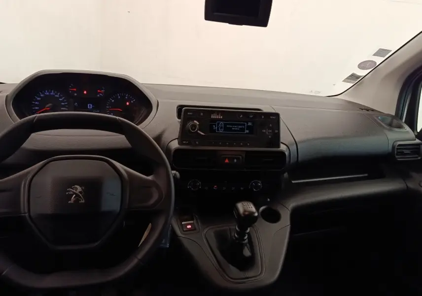 Vue intérieure du tableau de bord du Peugeot Partner blanc 2022, avec volant, écran central et levier de vitesses manuel.