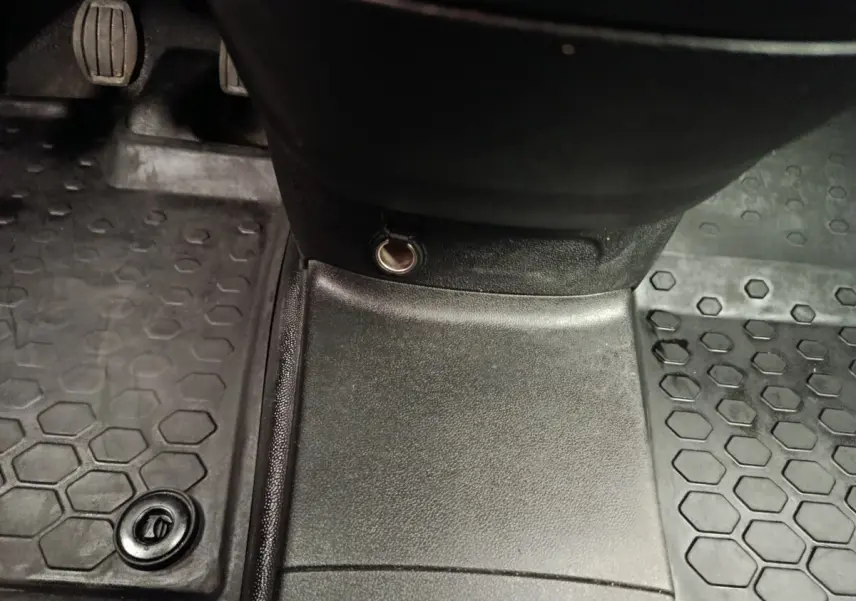 Vue rapprochée de la console centrale et des pédales d’un Peugeot Partner blanc, avec prise 12V visible.