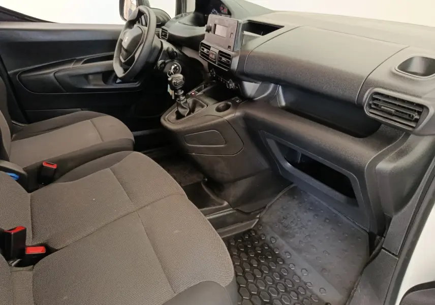 Vue intérieure côté conducteur du Peugeot Partner 2022, montrant les sièges gris, le volant et la console centrale avec boîte manuelle.