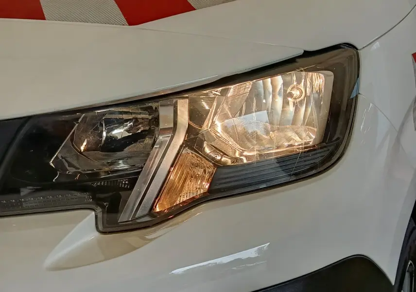 Gros plan sur le phare avant droit blanc du Peugeot Partner 2022, mettant en valeur les détails du bloc optique.