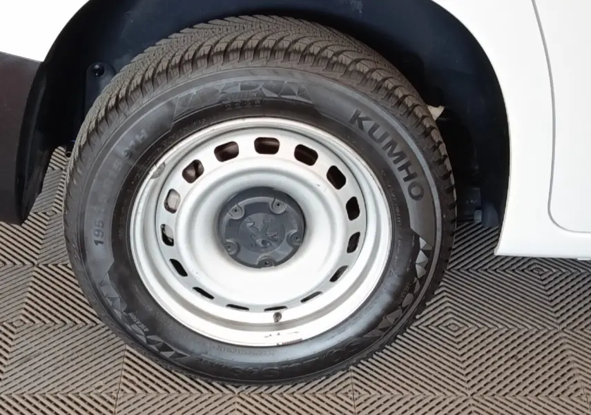 Gros plan sur la roue avant droite acier blanche d’un Peugeot Partner blanc 2022, avec pneu Kumho visible.