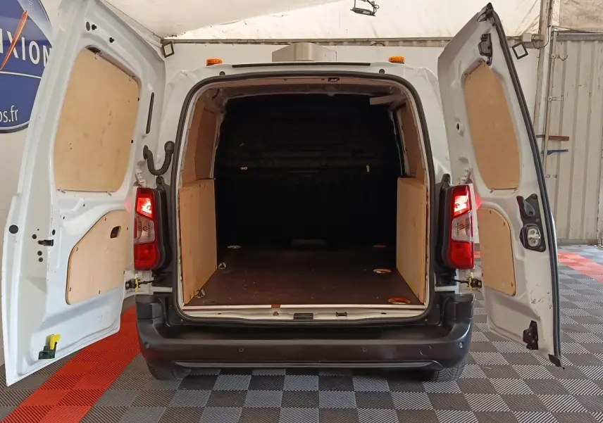 Vue arrière ouverte du Peugeot Partner blanc 2022 montrant l'espace de chargement avec cloison pleine et panneaux bois.