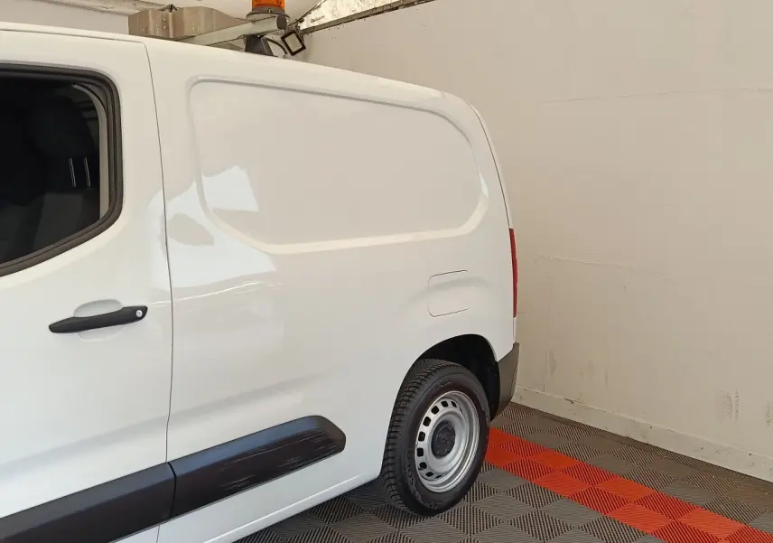 Vue latérale droite arrière d’un utilitaire Peugeot Partner blanc avec porte latérale pleine et jante acier.