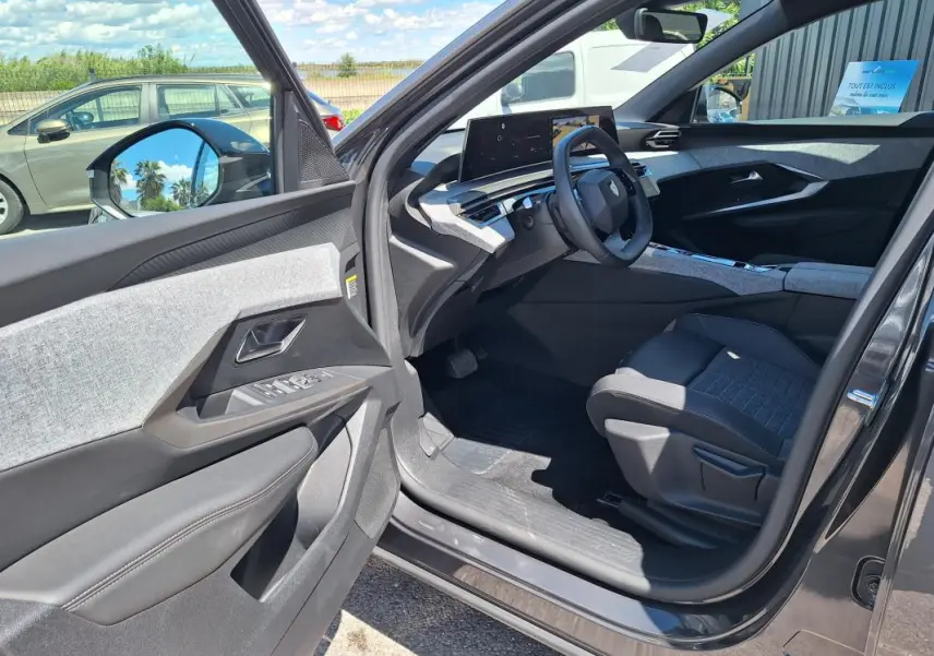 Vue intérieure côté conducteur du Peugeot 3008 Hybrid gris foncé, mettant en valeur le cockpit numérique et les finitions modernes.
