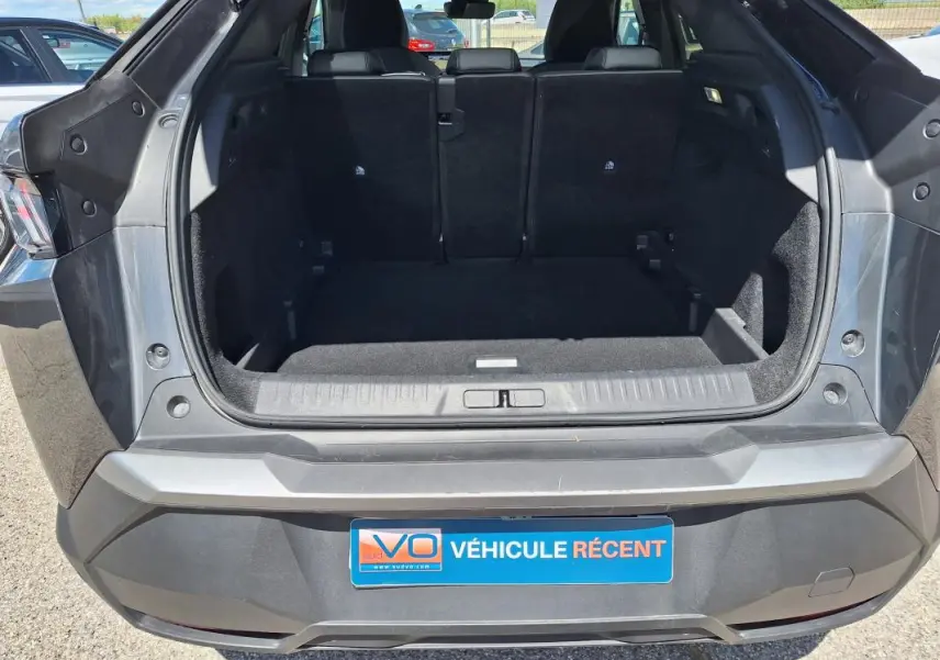 Coffre ouvert d’un Peugeot 3008 Hybrid gris foncé, vue arrière montrant l’espace de chargement vide.