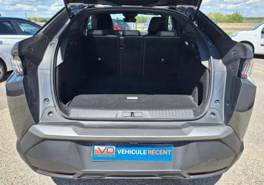 Coffre ouvert vu de l’arrière d’un Peugeot 3008 Hybrid gris foncé, montrant l’espace de chargement vide.