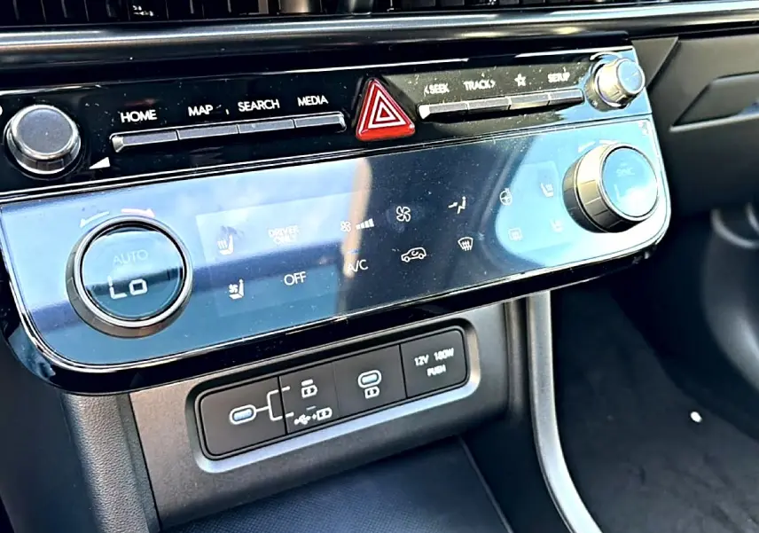 Vue rapprochée de la console centrale du Hyundai Tucson 2026, avec commandes climatisation et ports USB visibles.