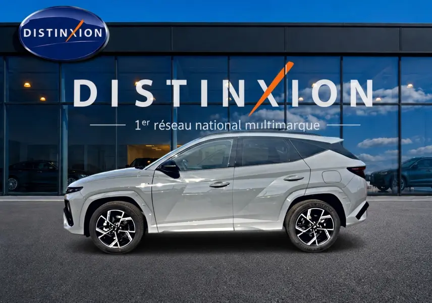 Vue de profil côté gauche du Hyundai Tucson 2026 gris shadow avec jantes alliage et toit noir devant showroom Distinxion.