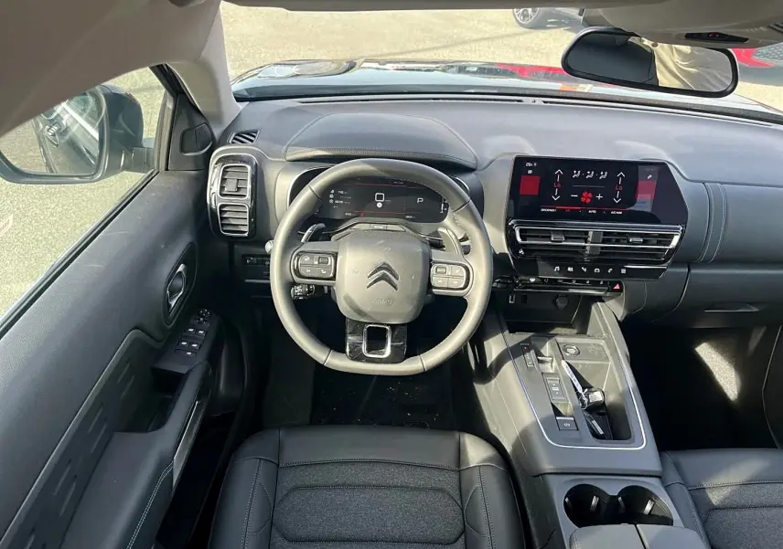 Vue intérieure avant du Citroën C5 Aircross 2025 noir, tableau de bord moderne avec écran tactile et volant cuir multifonction.