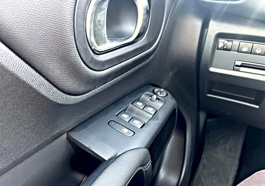 Gros plan sur la porte avant gauche noire du Citroën C5 Aircross 2025 avec commandes des vitres et poignée chromée.