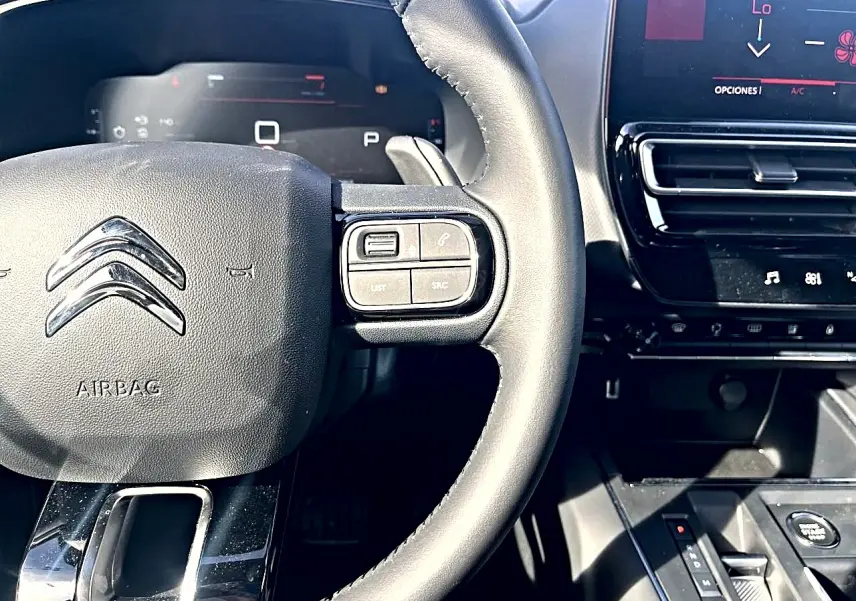 Vue rapprochée du volant cuir noir de la Citroën C5 Aircross 2025 avec commandes intégrées et tableau de bord numérique.