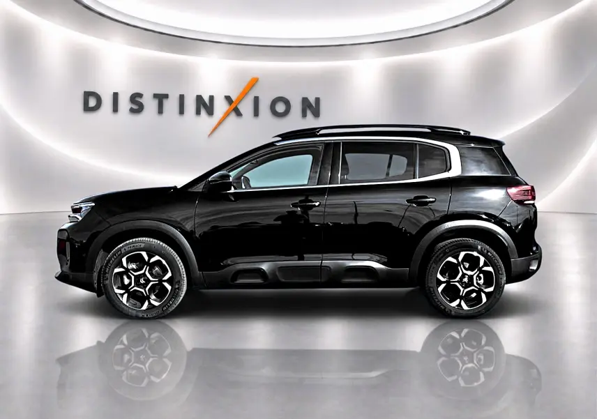 Profil droit du Citroën C5 Aircross noir 2025 avec jantes alu et barres de toit, sur fond blanc lumineux.