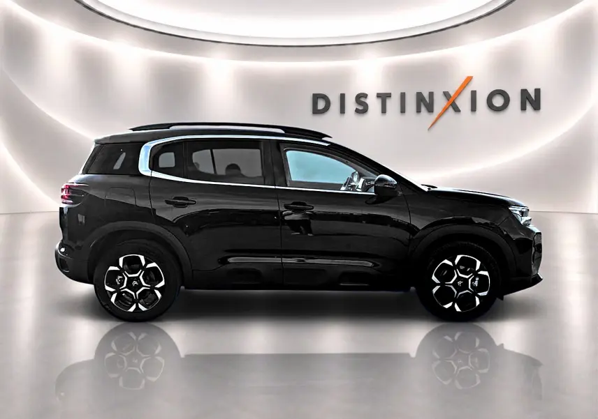 Profil droit noir brillant du Citroën C5 Aircross 2025 avec jantes alu et barres de toit visibles en studio.