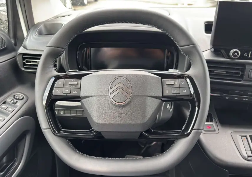 Vue rapprochée du volant multifonctions en cuir du Citroën Berlingo 2026 avec tableau de bord et écran tactile.