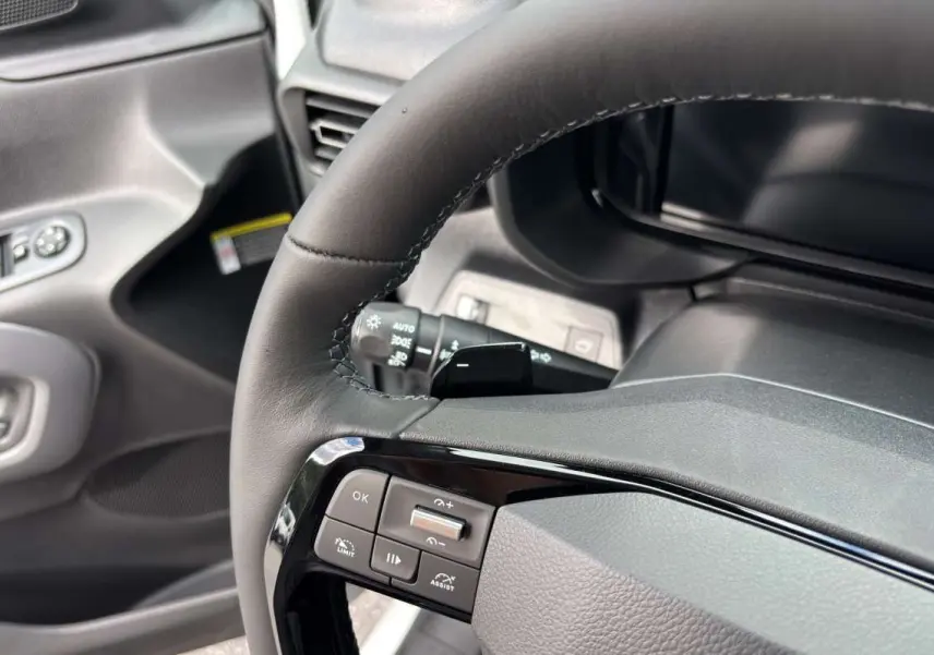 Gros plan sur le volant cuir noir multifonctions du Citroën Berlingo 2026 avec commandes intégrées et tableau de bord gris.
