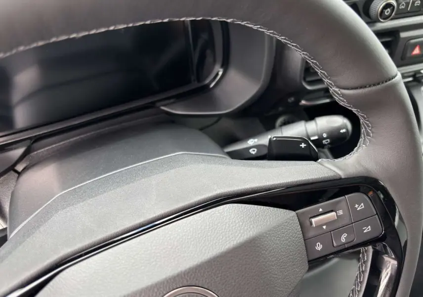 Gros plan sur le volant cuir multifonctions du Citroën Berlingo 2026, avec commandes intégrées et palettes au volant.