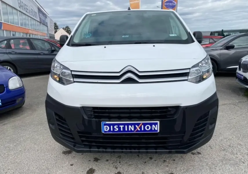 Vue frontale d’un utilitaire Citroën Jumpy blanc avec pare-chocs noir et plaque Distinxion visible.