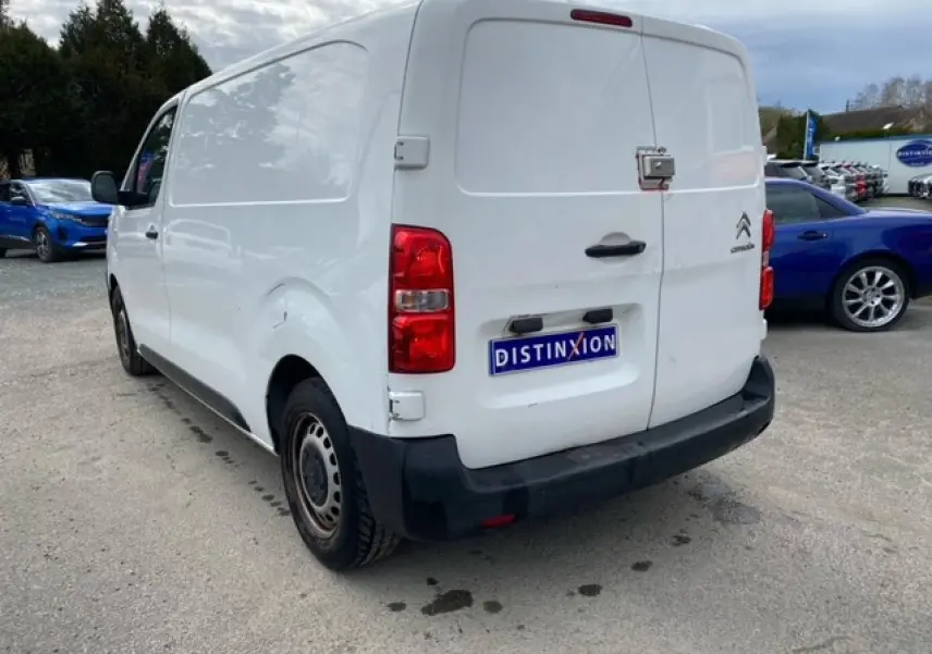 Vue 3/4 arrière droite d'un utilitaire Citroën Jumpy blanc avec portes arrière battantes et pare-chocs noir.