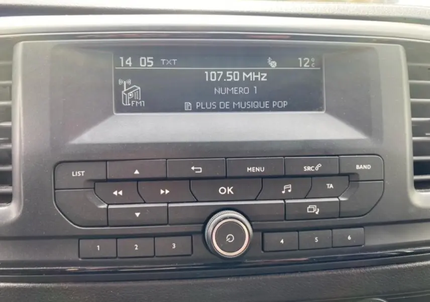 Gros plan sur l'autoradio du Citroën Jumpy blanc 2019 affichant la fréquence 107.50 MHz et la température extérieure 12°C.