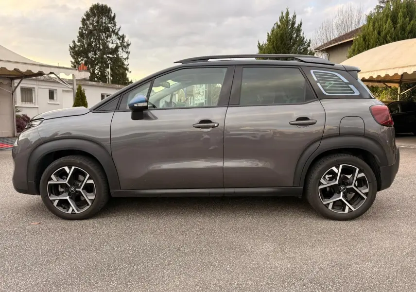Vue de profil côté gauche d'un Citroën C3 Aircross gris platinium avec jantes alliage et toit noir contrasté.
