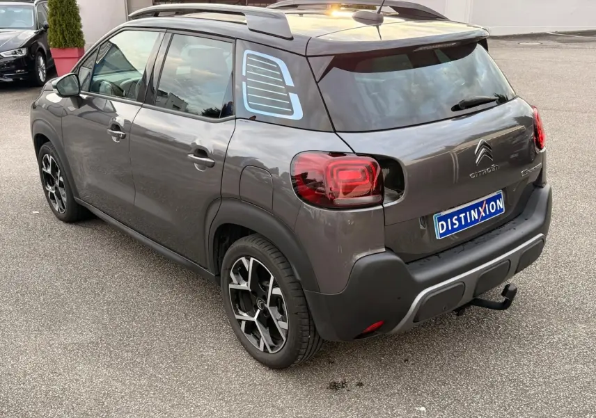 Vue 3/4 arrière droite d'une Citroën C3 Aircross gris platinium avec jantes noires et toit noir contrasté.